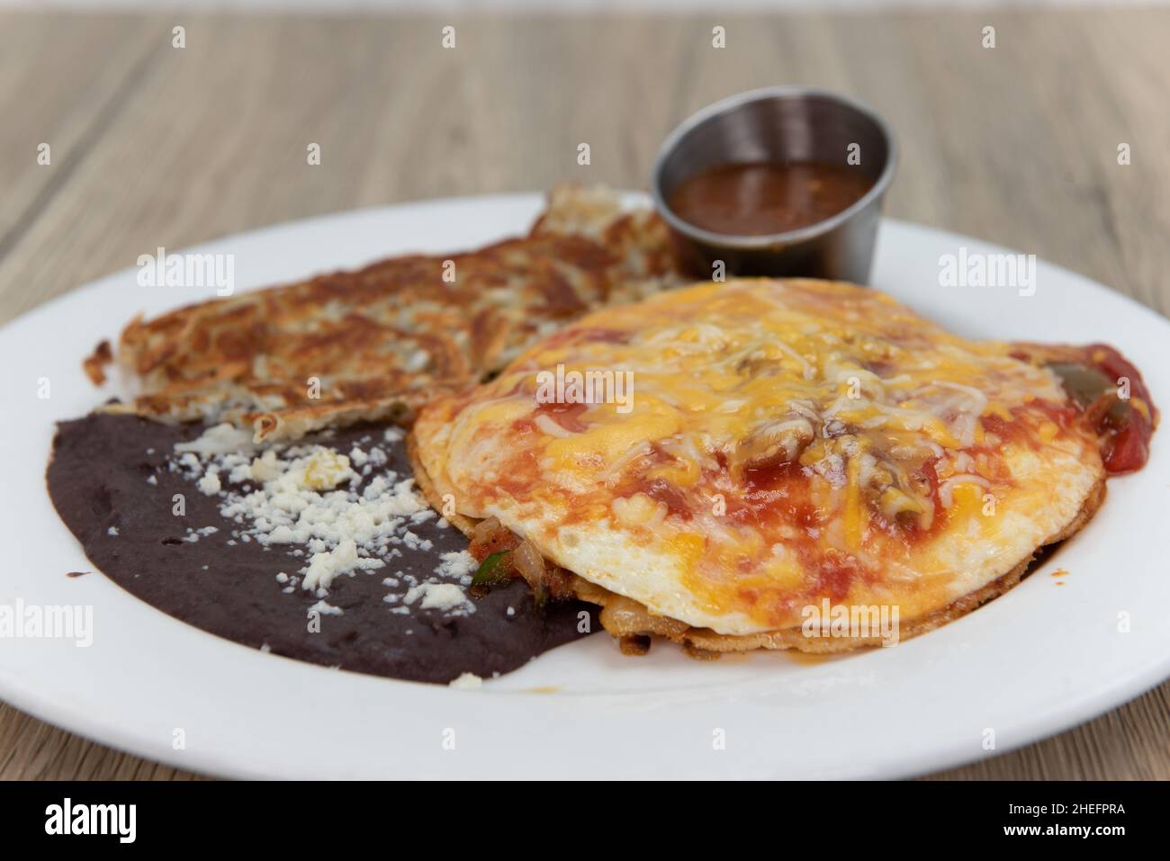 Huevos rancheros con uova, fagioli fritti, hashbrown per una deliziosa colazione messicana per iniziare la giornata. Foto Stock