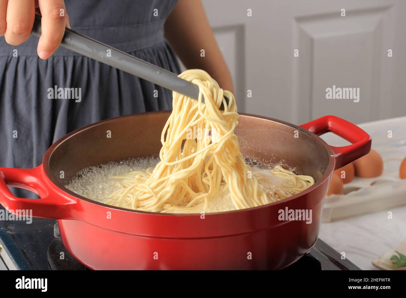 Asian Female bollito a mano Asian Noodle (mie Telur o bakmi), processo di cottura in cucina Foto Stock