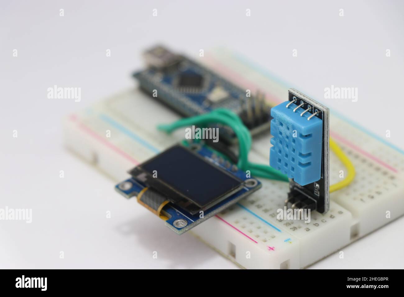 DHT11 o sensore di temperatura e umidità con circuito di visualizzazione OLED su una breadboard gestita da un microcontrollore sullo sfondo Foto Stock