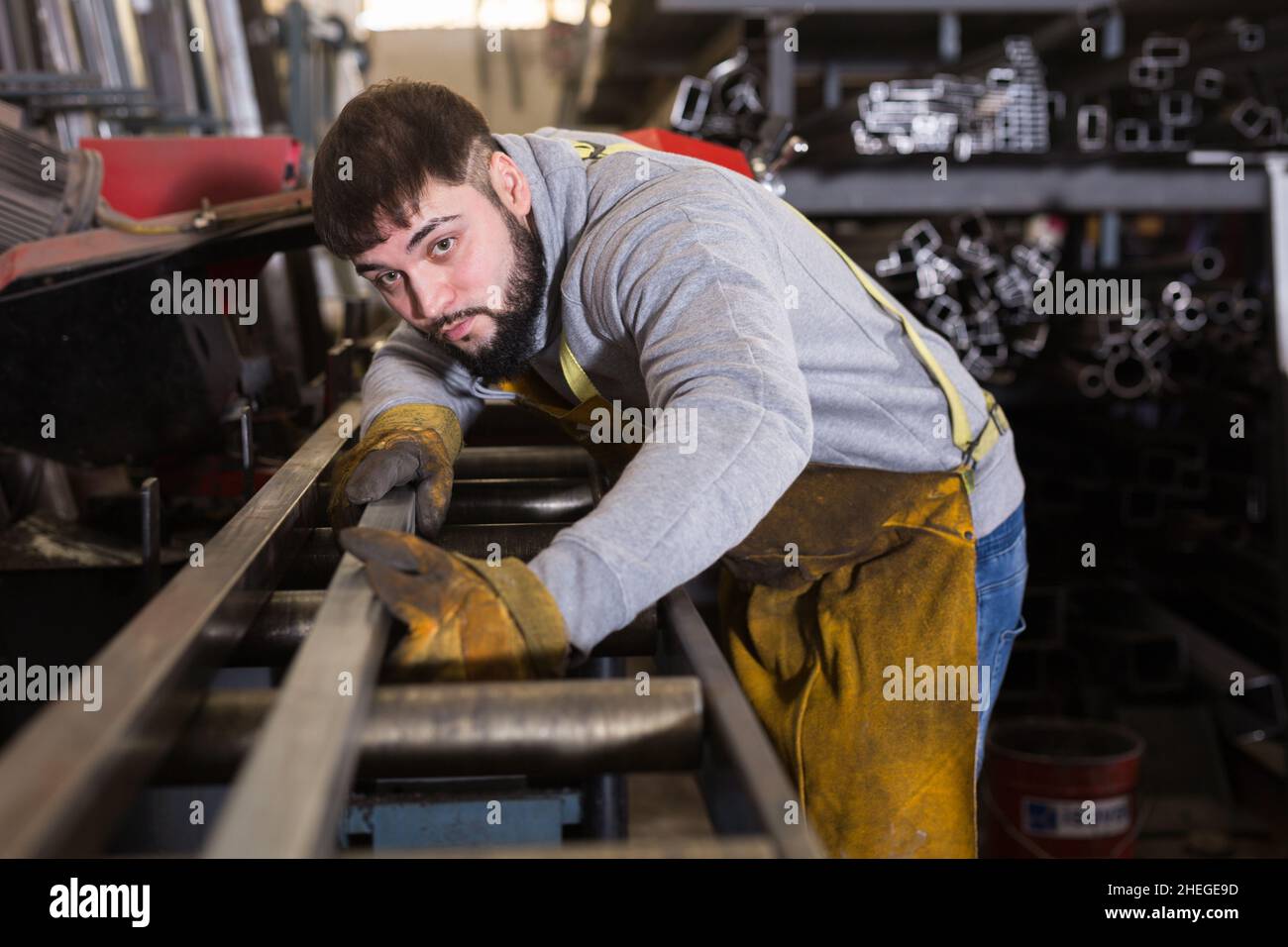 L'operatore taglia il tubo di profilo metallico su una sega a nastro Foto Stock