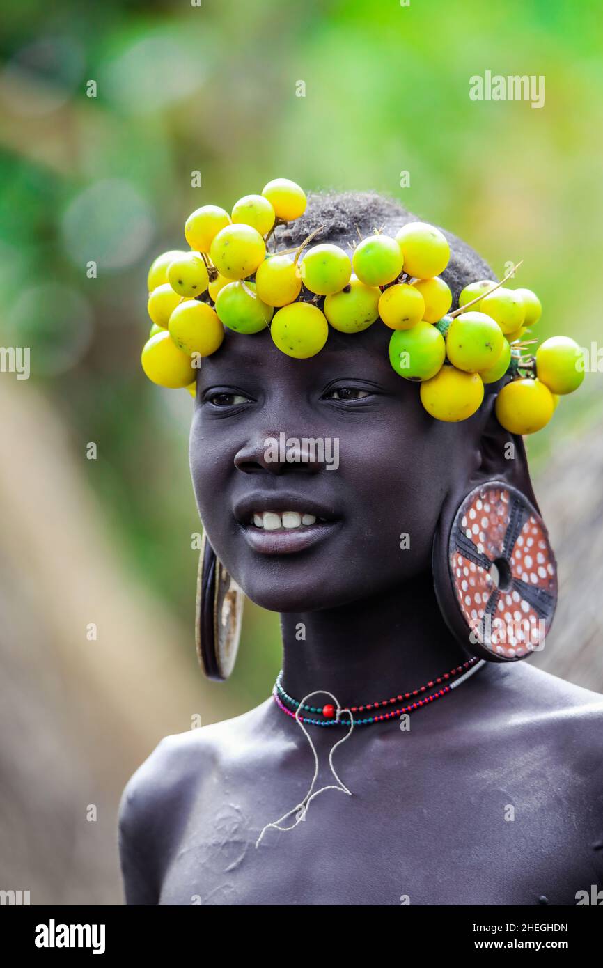 Omo River Valley, Etiopia - 29 novembre 2020: Ritratto di Teenager africano  con grandi orecchini tradizionali in legno e corona di fiori gialli secchi  Foto stock - Alamy