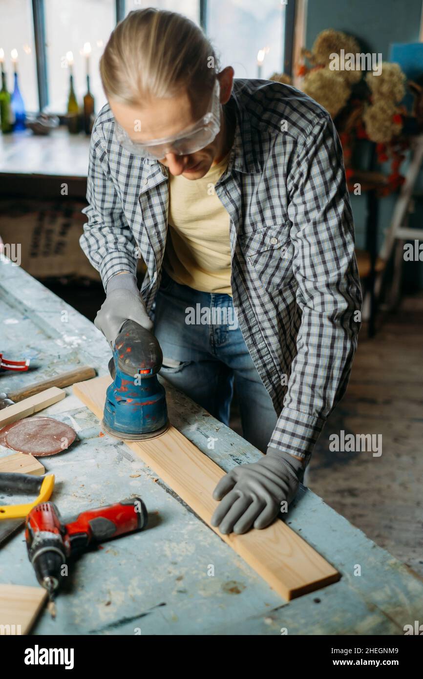 Uomo che lavora in officina, fa mobili, riutilizza vecchi materiali per nuovi prodotti. Consapevolezza nel consumo. Piccola impresa. Riciclaggio, sostenibilità Foto Stock