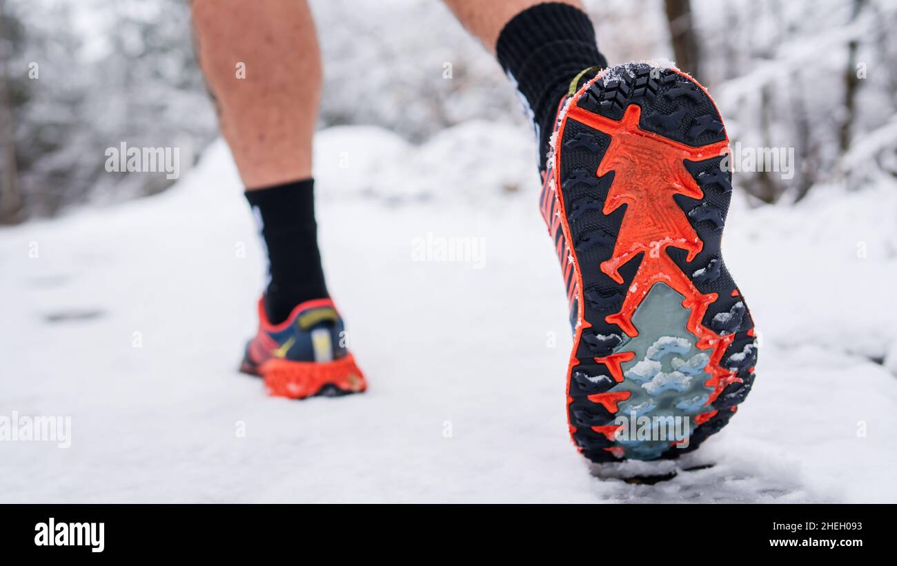 uomo sconosciuto che corre nella neve in inverno primo piano su scarpe da ginnastica Foto Stock