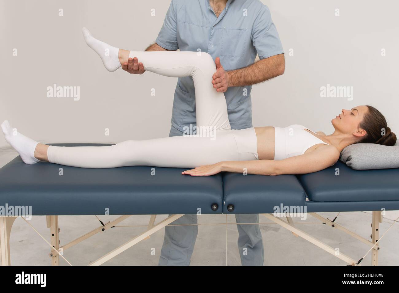 Sollievo dal dolore al ginocchio in clinica. Medico fisioterapista che fa il trattamento healing sulla gamba del paziente. Terapista che dà massaggio a gambe e vitelli. Osteopatia Foto Stock