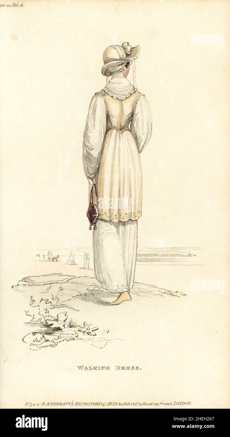 Regency donna passeggiando su una spiaggia, 1811. Abito di finissima mussola jaconot, bordi a mezzaluna con lavorazione dell'ago, cappotto romano corto, rifinito con pizzo francese, cappello di montagna sopra un cappellino fondente. Targa 22, ottobre 1 1811. Foto Stock