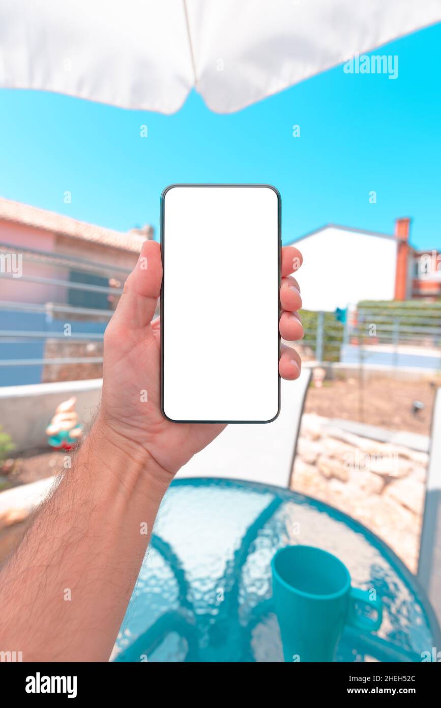 Cellulare smart phone mockup schermo, uomo che gode la vacanza estiva in appartamento terrazza e dispositivo di tenuta, primo piano con fuoco selettivo Foto Stock
