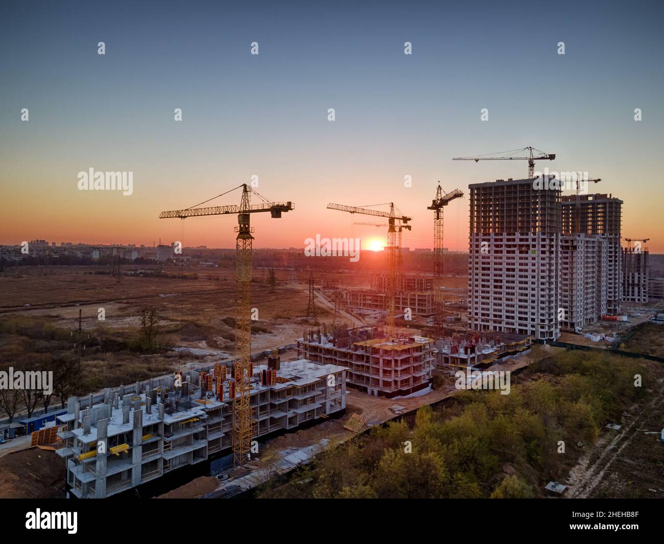 Tramonto su un cantiere con gru che costruisce nuove case Foto Stock