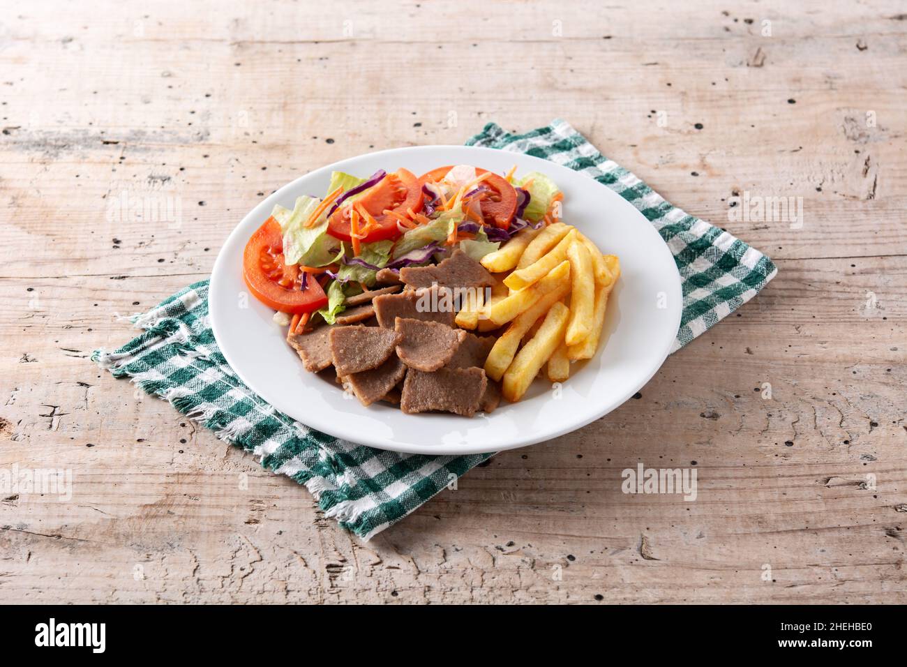 Piatto di kebab, verdure e patatine fritte su tavola di legno Foto Stock