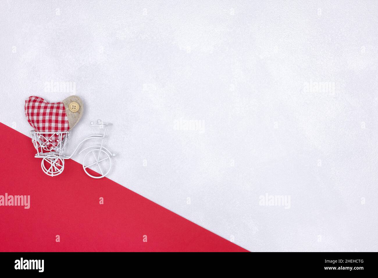 Piccola bicicletta giocattolo bianca con cuore tessile rosso. Spazio di copia. San Valentino semplice cute sfondo Foto Stock