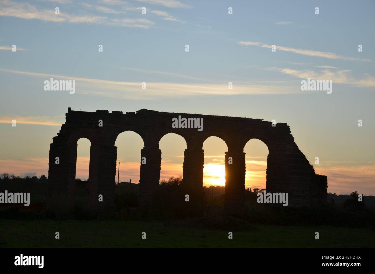 Foto scattate al tramonto durante una passeggiata attraverso il bellissimo Parco degli acquedotti di Roma, con le maestose rovine di antichi acquedotti e alberi romani Foto Stock