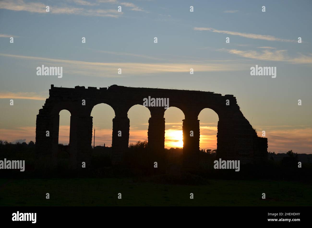 Foto scattate al tramonto durante una passeggiata attraverso il bellissimo Parco degli acquedotti di Roma, con le maestose rovine di antichi acquedotti e alberi romani Foto Stock