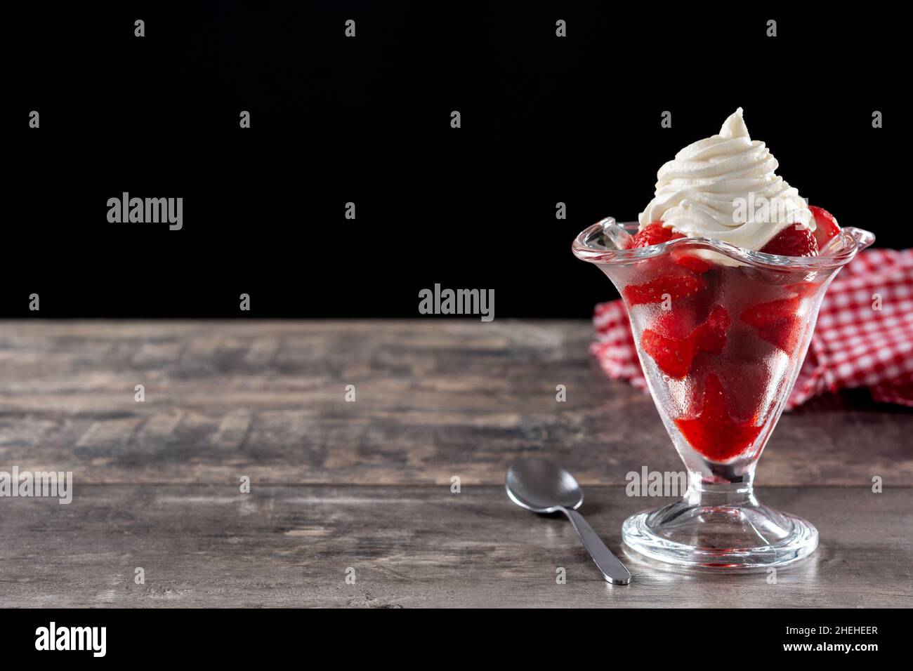 Fragole e panna montata in un bicchiere di gelato su un tavolo di legno Foto Stock