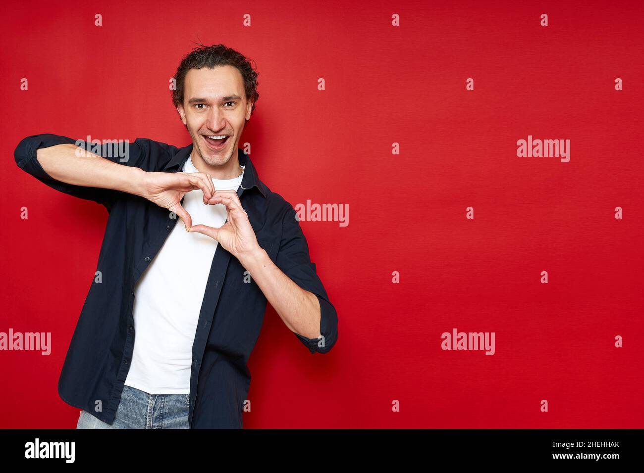 l'uomo allegro eccitato mostra segno di cuore con le mani davanti al petto, confessa il suo amore. Foto Stock