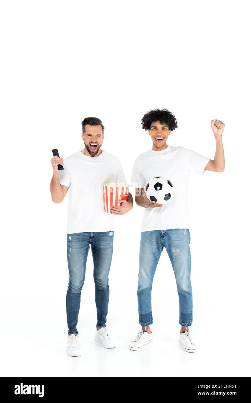 entusiasti appassionati di sport interrazziali con pallone da calcio e popcorn che guardano la partita di calcio in tv su bianco Foto Stock