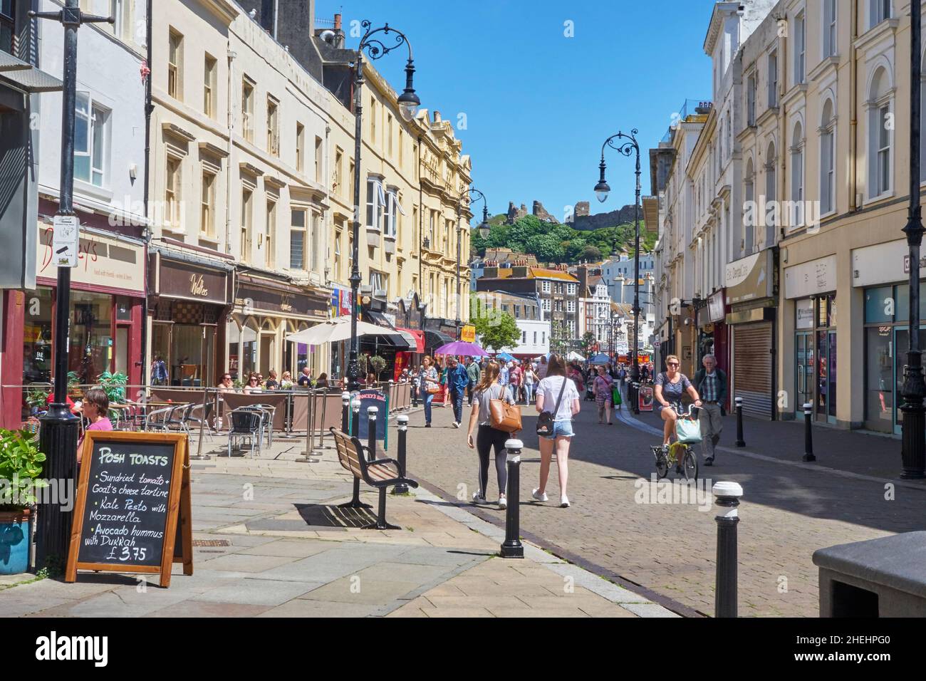 Hastings, la vista lungo le caffetterie e i bar di Robertson Street verso la cima della collina del Castello normanno, East Sussex, England, Regno Unito, Regno Unito, Gran Bretagna Foto Stock