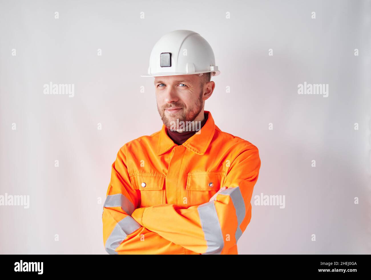 Sorridente lavoratore di costruzione o tecnico in elmetto. Supervisore o architetto di costruzione con bearded maschio in elmetto bianco e giubbotto riflettente arancione di sicurezza. Foto di alta qualità Foto Stock