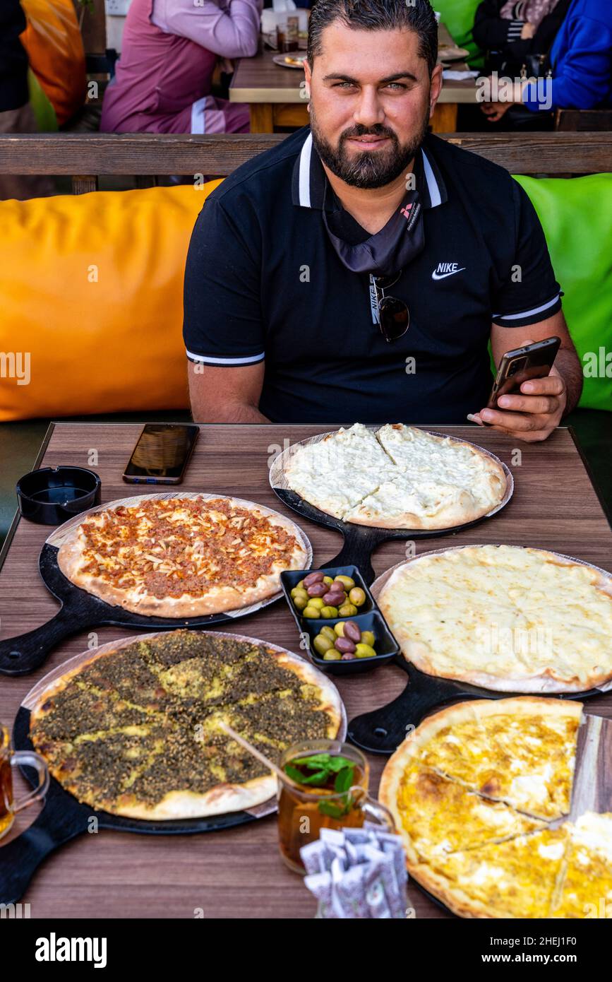 Un uomo Giordano che mangia Una colazione tradizionale di pani piatti, Aqaba, governorato di Aqaba, Giordania. Foto Stock