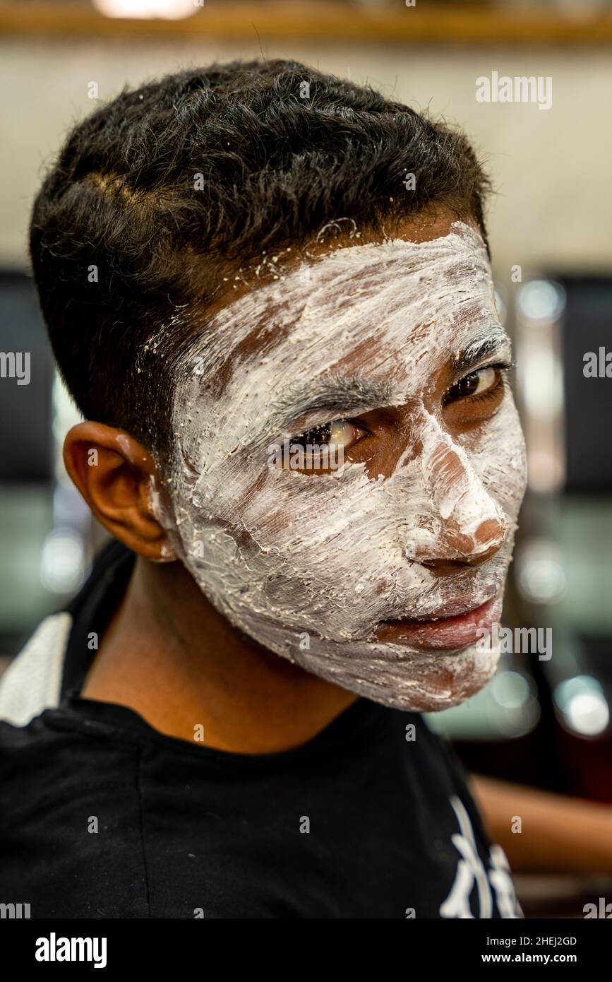 Un giovane uomo in Un salone di parrucchiere che indossa un Face Pack, Aqaba, Aqaba Governorate, Giordania. Foto Stock