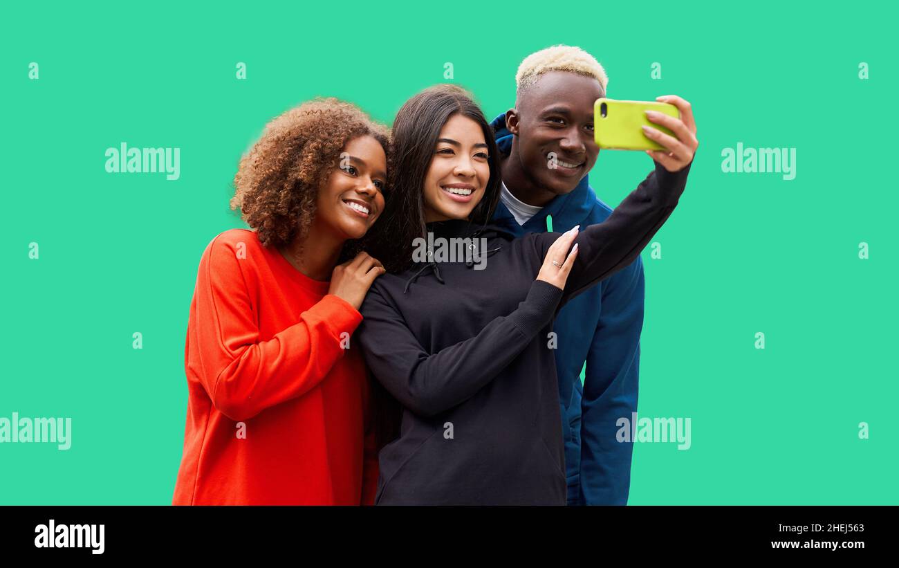 Studio girato di giovani amici multiculturali carini. Bella gente sorridente allegro e divertirsi mentre si fa selfie foto. Backgrou verde isolato Foto Stock