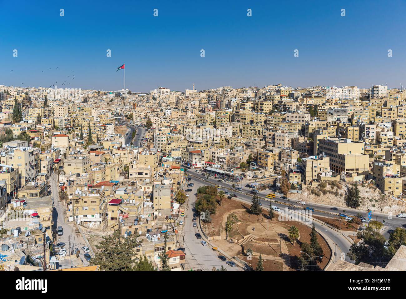 AMMAN, GIORDANIA - 27 DICEMBRE 2021: Vista della città di Amman con la bandiera giordana gigante sullo sfondo Foto Stock