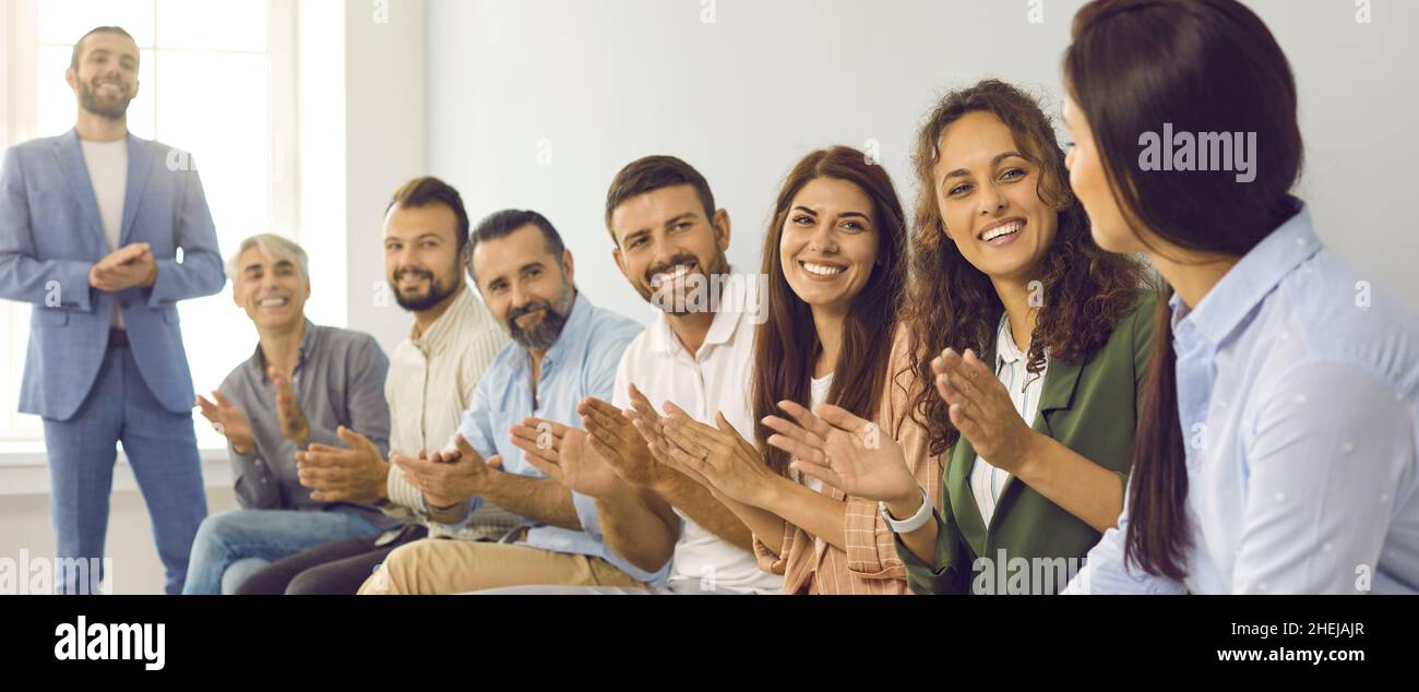 Un team di lavoro felice che applaude il collega e che dimostra apprezzamento per il suo lavoro Foto Stock