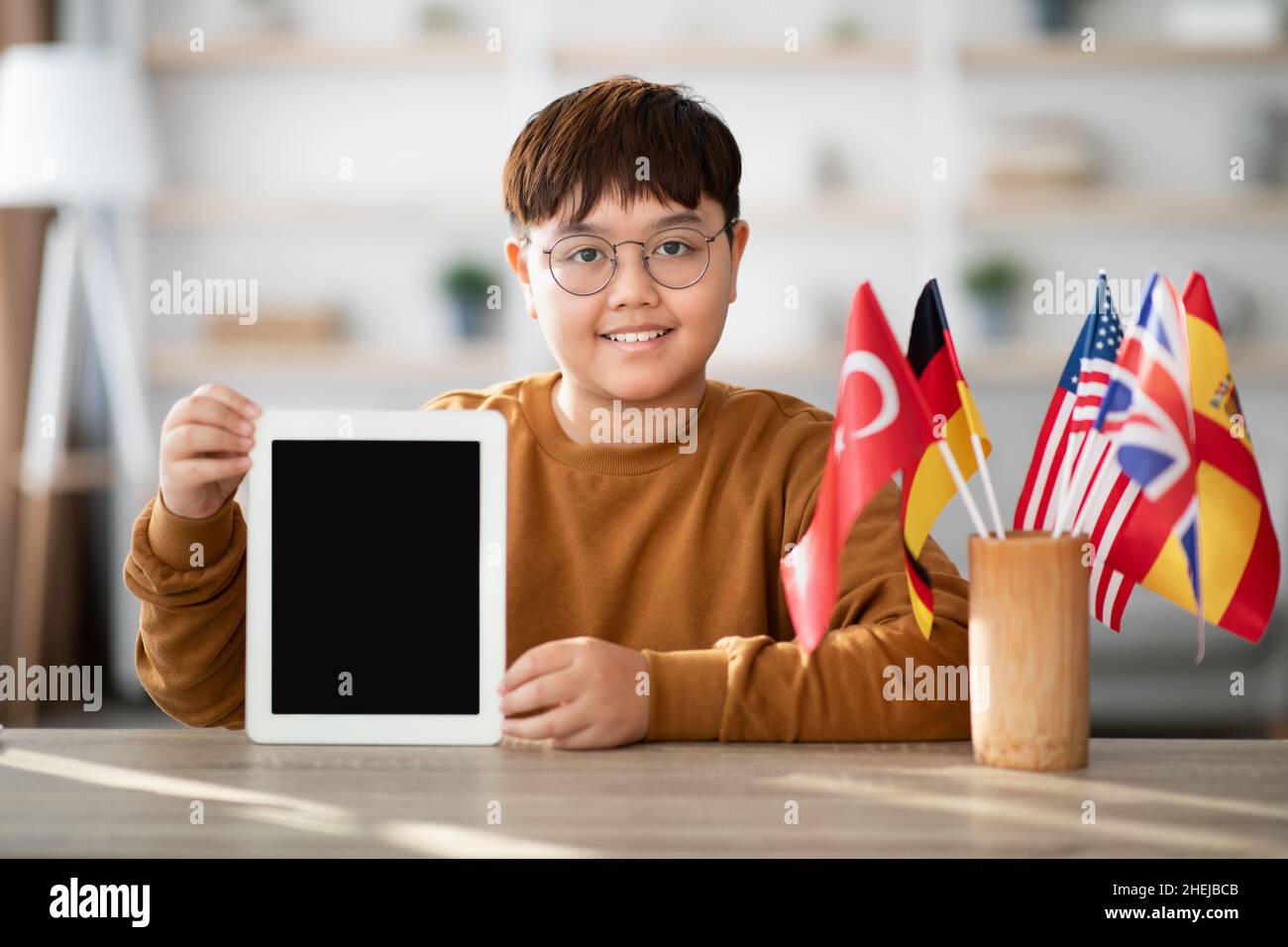 Positivo ragazzo asiatico chubby mostrando tablet digitale con schermo vuoto Foto Stock