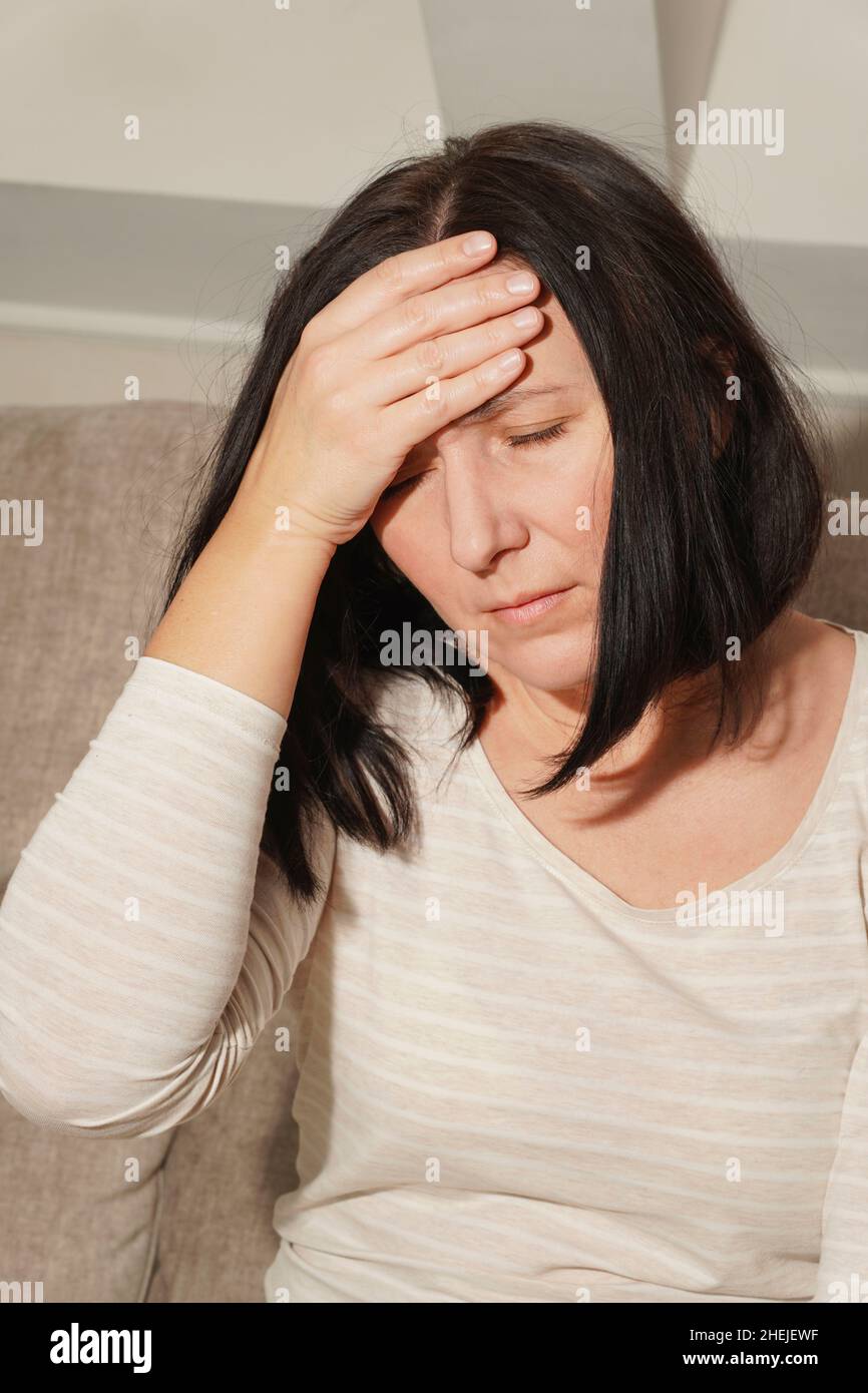 Donna matura di mezza età che ha mal di testa, emicrania. Donna nel dolore, triste, stanca, stressata. Foto Stock