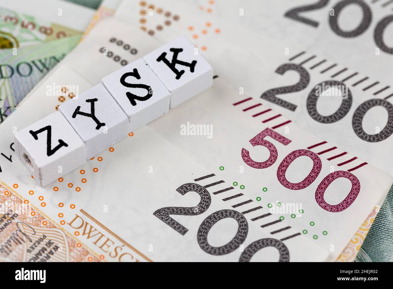 La dicitura 'Zysk' tradotta come 'profitto' più molte banconote polacche. Foto scattata sotto luce artificiale e soffusa Foto Stock