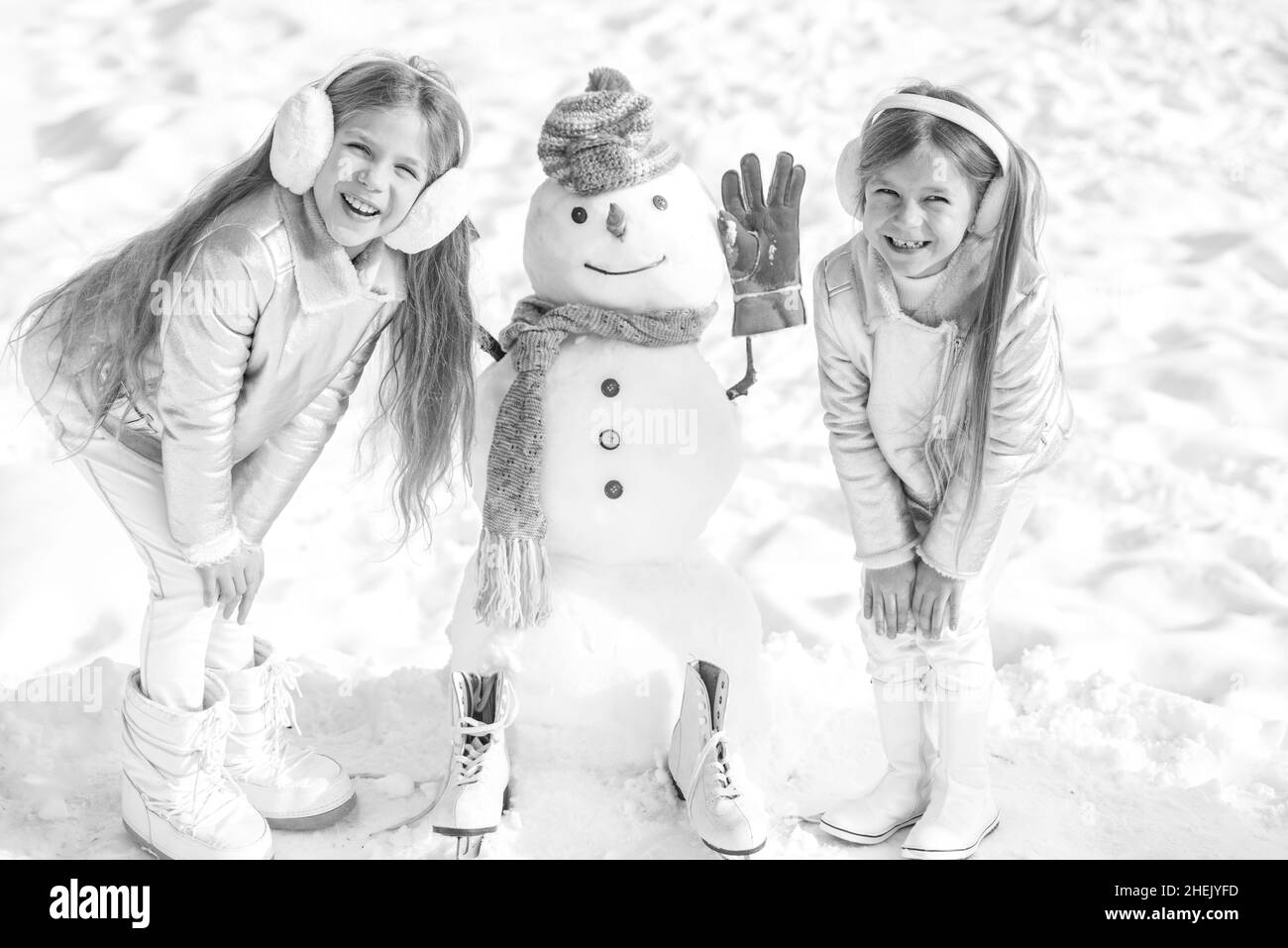 Tema Natale vacanze inverno nuovo anno. Bambini felici che giocano con un pupazzo di neve in una passeggiata invernale nevosa. Foto Stock