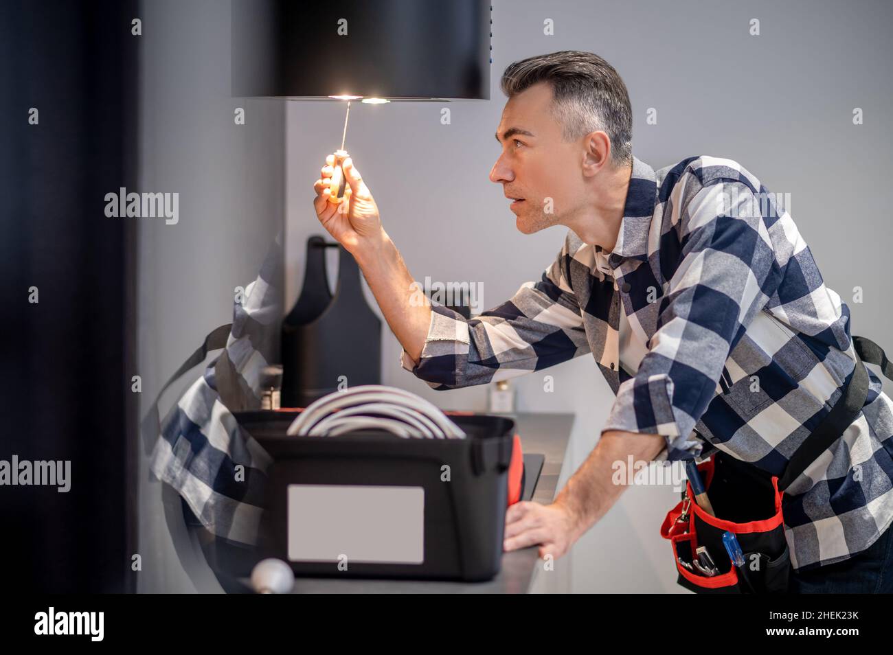 Profilo di uomo a contatto lampada su cappa da cucina Foto Stock