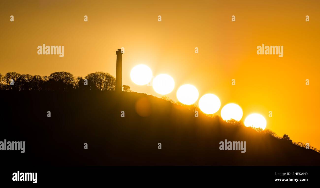Composto di sole tramonta sulle colline con la silhouette della torre Hopetoun Monument in cima alla collina, East Lothian, Scozia, Regno Unito Foto Stock