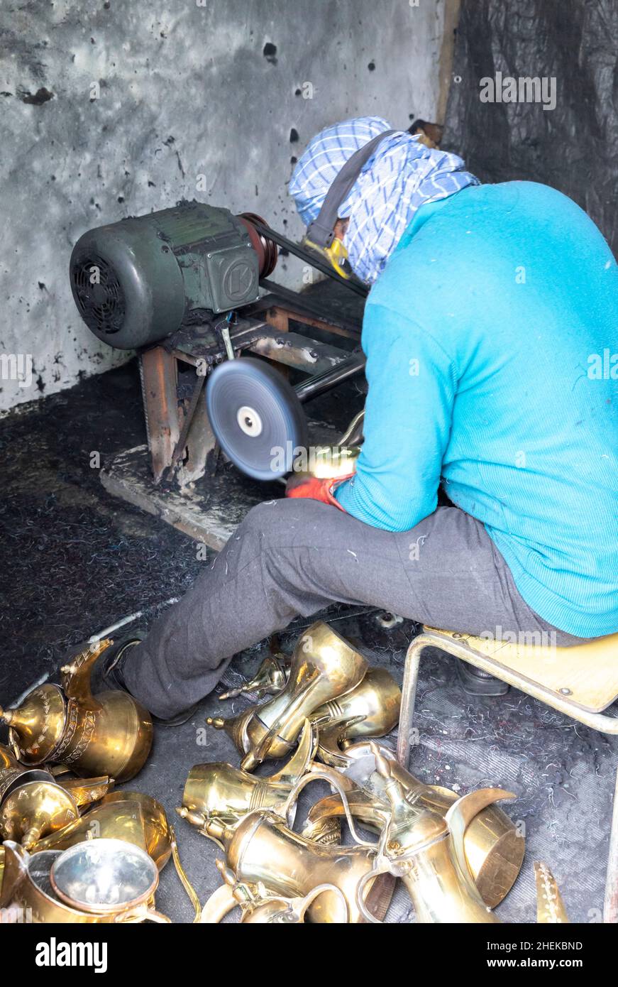 Ushaiqer, Arabia Saudita, 1st gennaio 2022: Uomo che lavora in un laboratorio polveroso, la produzione di caffè arabo pentole Foto Stock