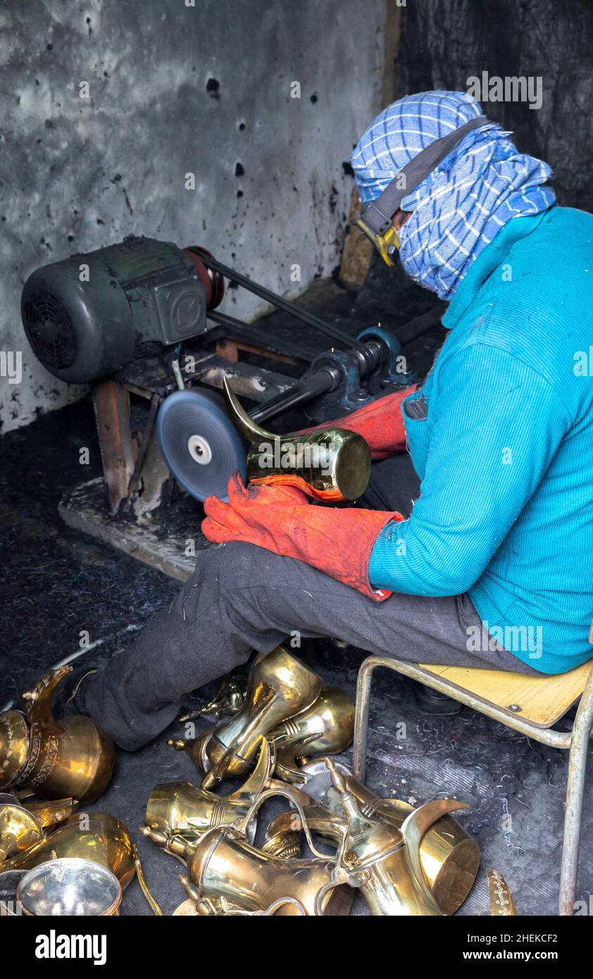 Ushaiqer, Arabia Saudita, 1st gennaio 2022: Uomo che lavora in un laboratorio polveroso, la produzione di caffè arabo pentole Foto Stock