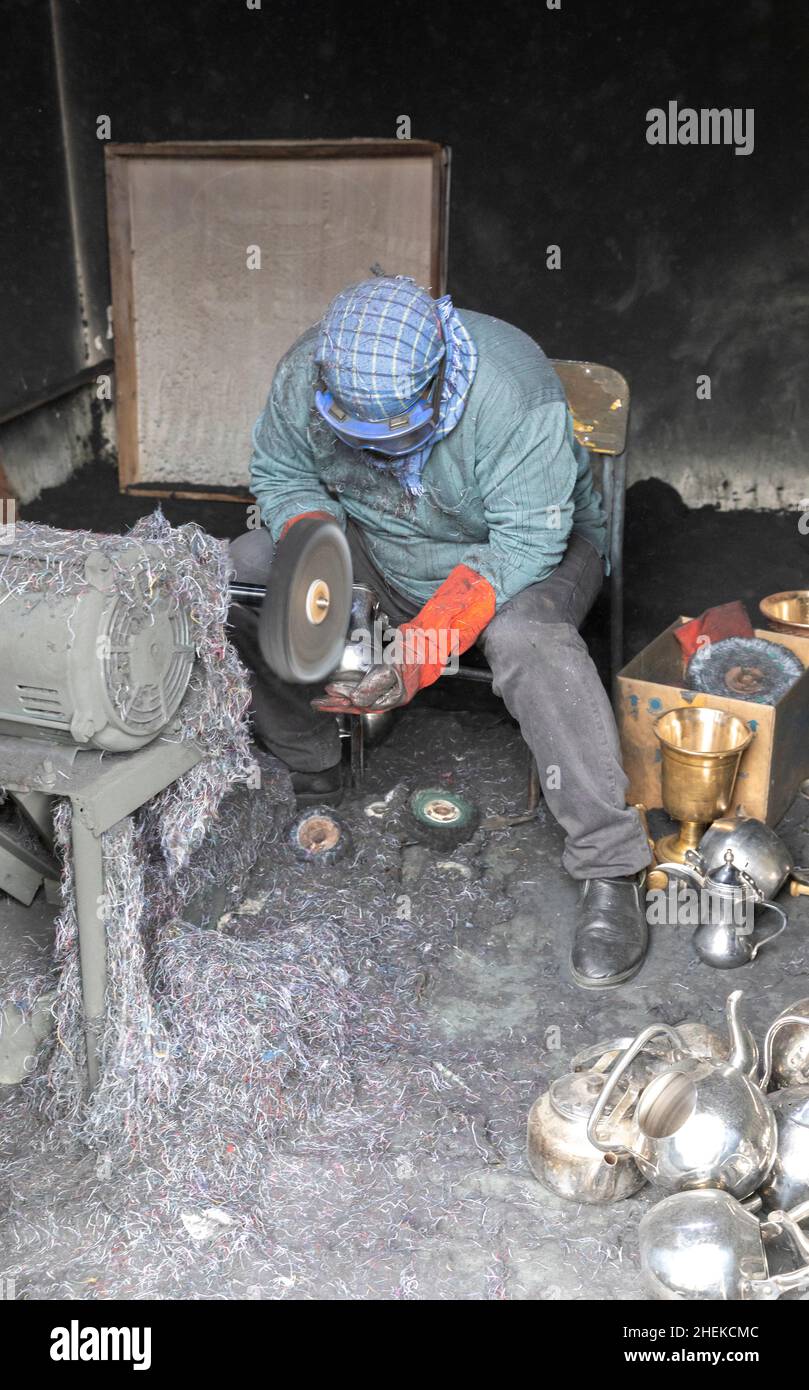 Ushaiqer, Arabia Saudita, 1st gennaio 2022: Uomo che lavora in un laboratorio polveroso, la produzione di caffè arabo pentole Foto Stock