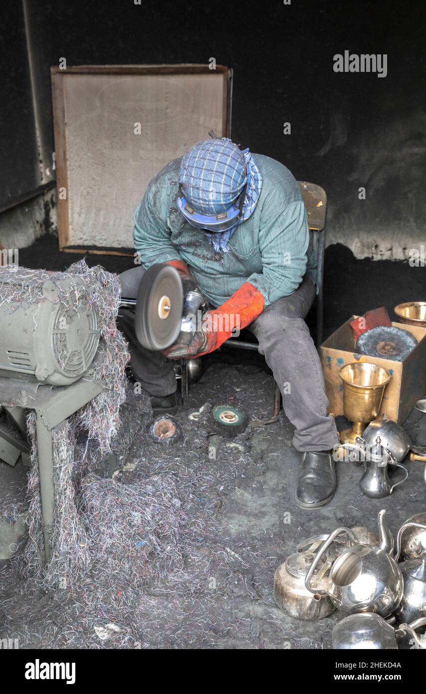 Ushaiqer, Arabia Saudita, 1st gennaio 2022: Uomo che lavora in un laboratorio polveroso, la produzione di caffè arabo pentole Foto Stock