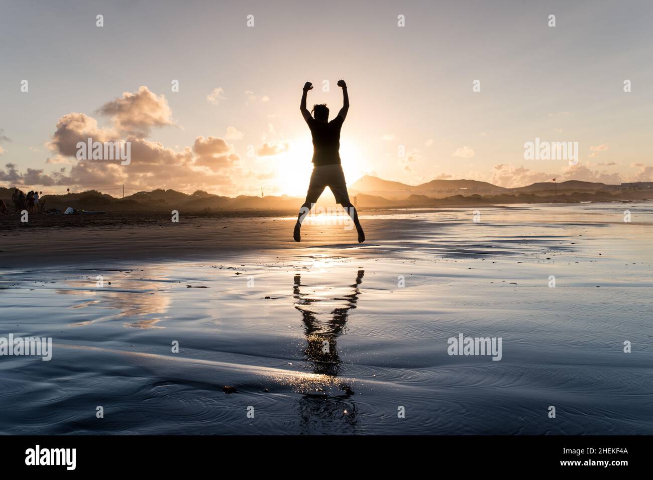 L'uomo felice salta sulla spiaggia con un bellissimo tramonto. Riuscito. Foto Stock