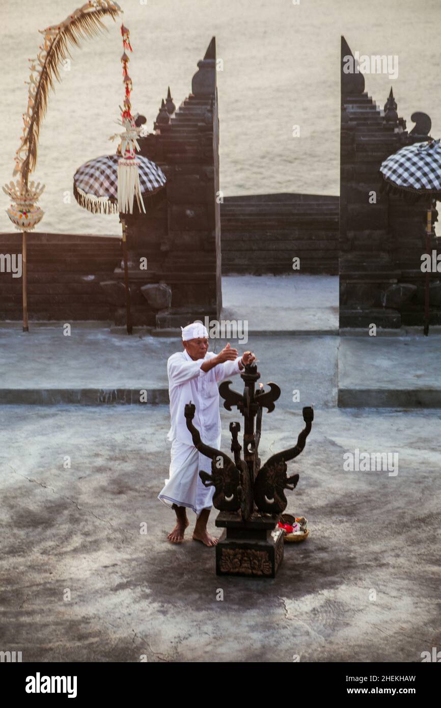 Bali - Indonesia - 10.21.2015: Old Balinese - Indonesiano uomo che illumina il fuoco per la tradizionale danza del fuoco Kecak che si svolge nella pura Luhur Foto Stock