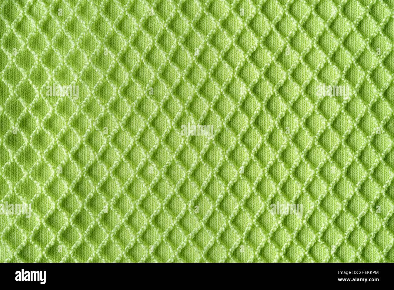 Maglia verde sopra cotone maglia macro texture. Sfondo di tessuto a maglia verde chiaro con mesh per casual e sportswear. Tessuto di abbigliamento moderno. Foto Stock