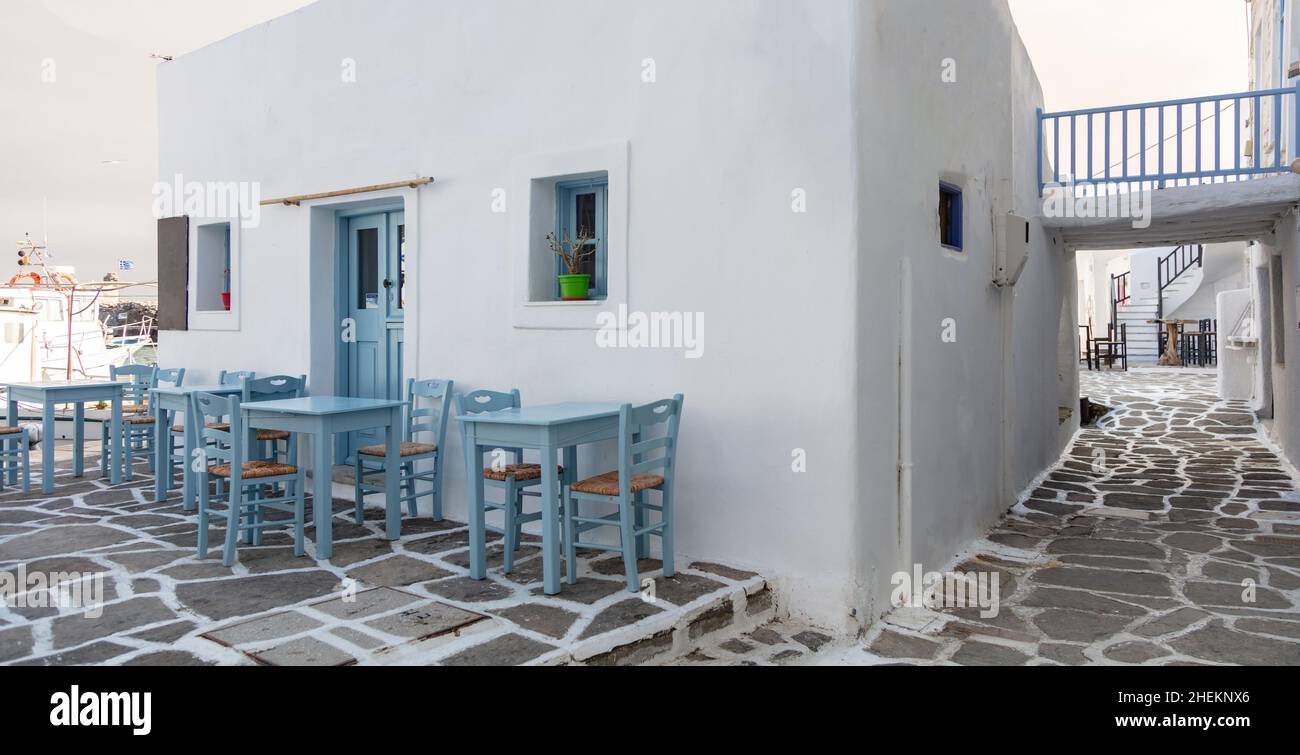 Grecia, Paros isola Naousa porto vecchio. Bar ristorante all'aperto, tavoli e sedie vuoti sul mare Foto Stock