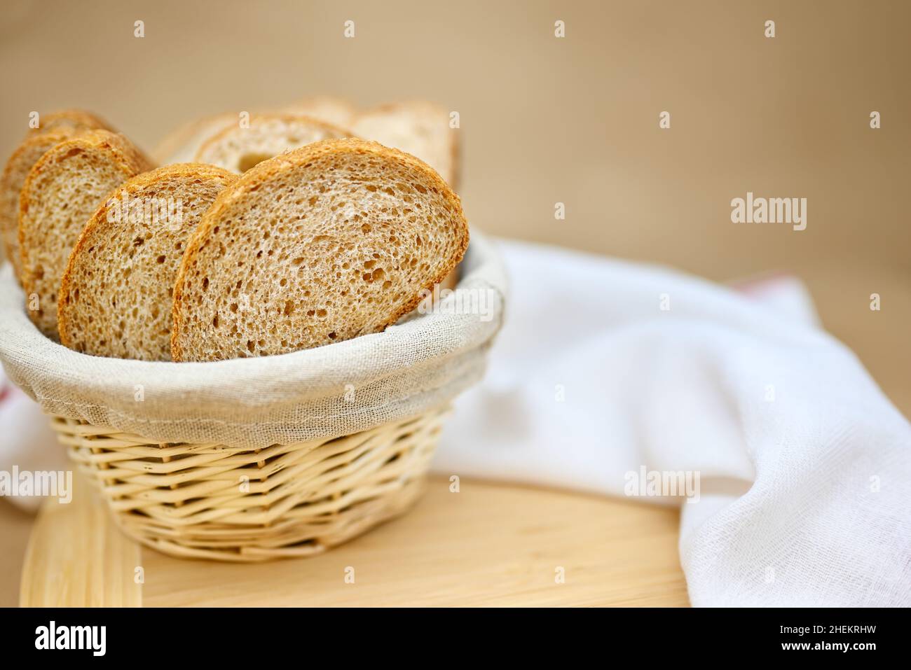 Pane fresco di cereali in un cestino di vimini. Il pane viene affettato.  Sfondo beige, asse di legno, panno di lino in un cestino, tisana bianca sul  tavolo Foto stock - Alamy