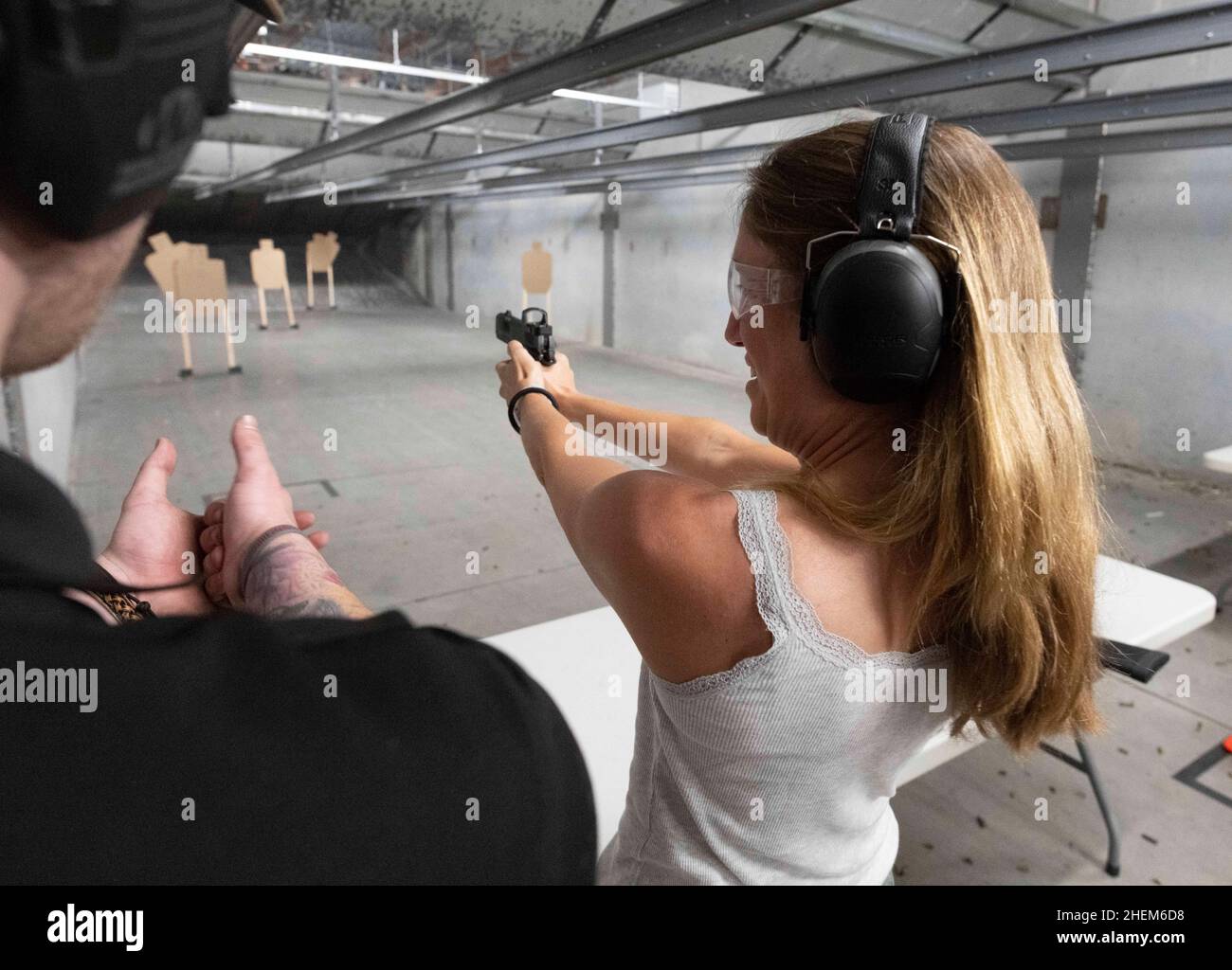 Austin Texas USA, ottobre 23 2021: La giornalista Claire Meynial riceve istruzioni mentre spara una pistola durante un incontro con il club Bitcoin al The Range, un luogo di tiro al coperto nel sud di Austin, dove i membri hanno girato centinaia di round ai bersagli. ©Bob Daemmrich Foto Stock