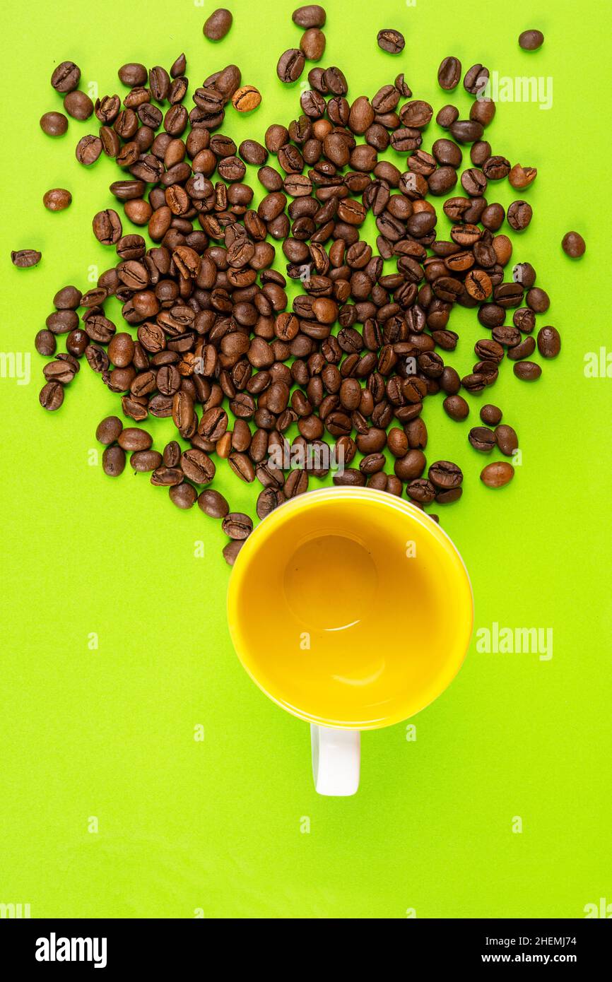 caffè in grani su una superficie gialla e una tazza colorata Foto Stock