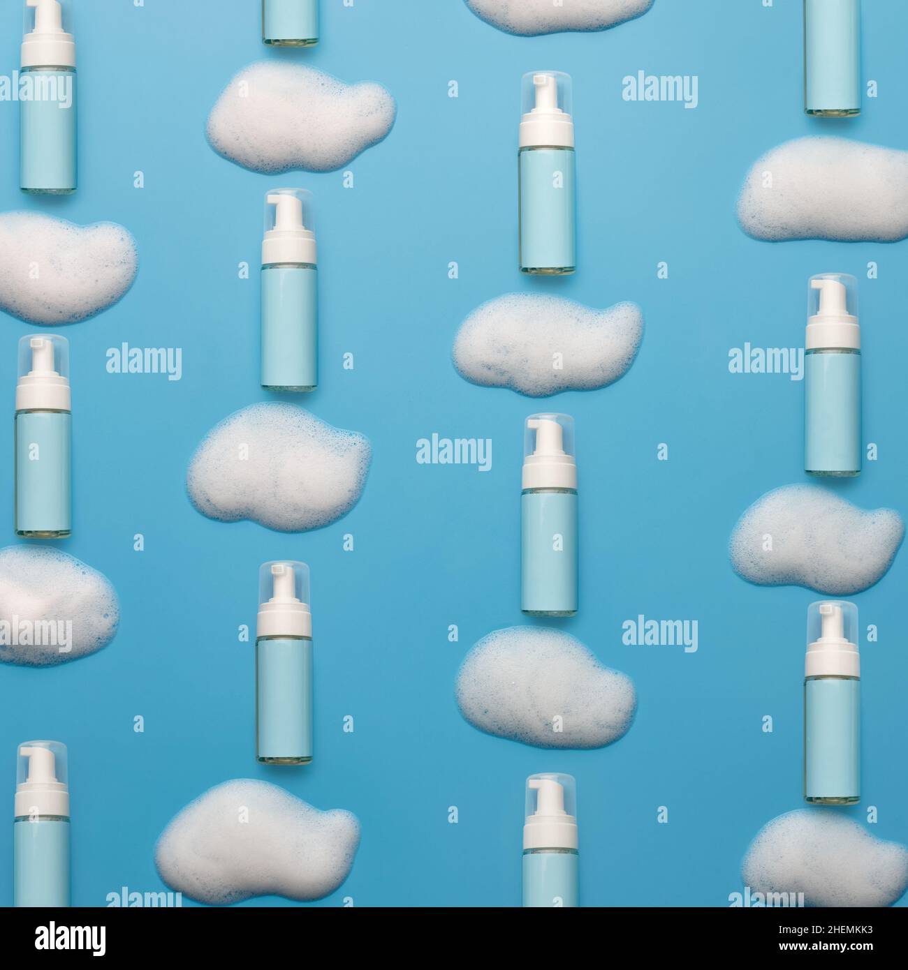 Modello creativo con nuvole di schiuma detergente e bottiglie cosmetiche Foto Stock