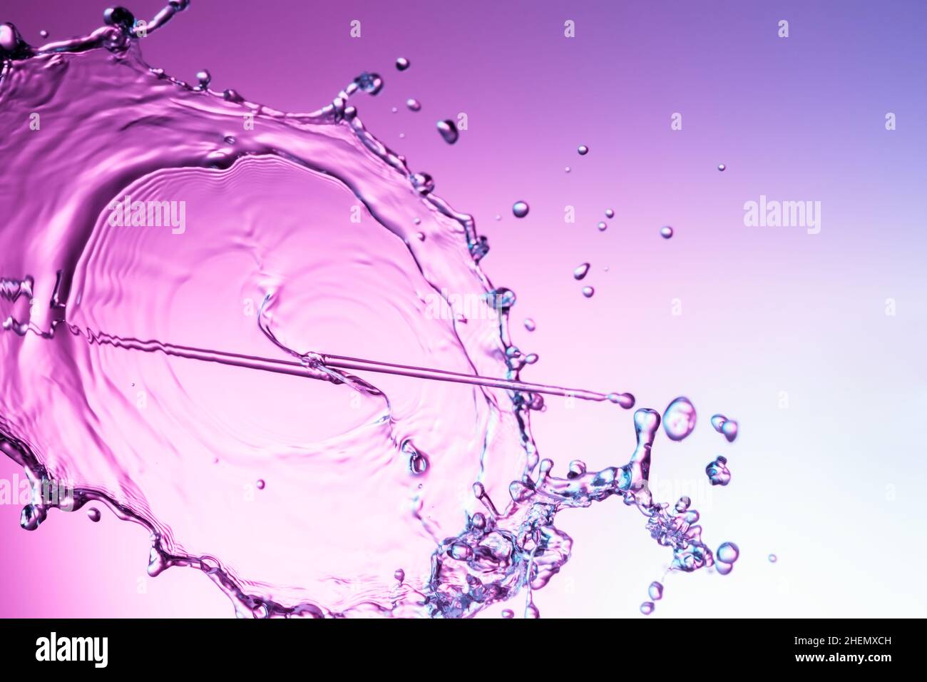 Spruzzi d'acqua limpida su sfondo viola Foto Stock