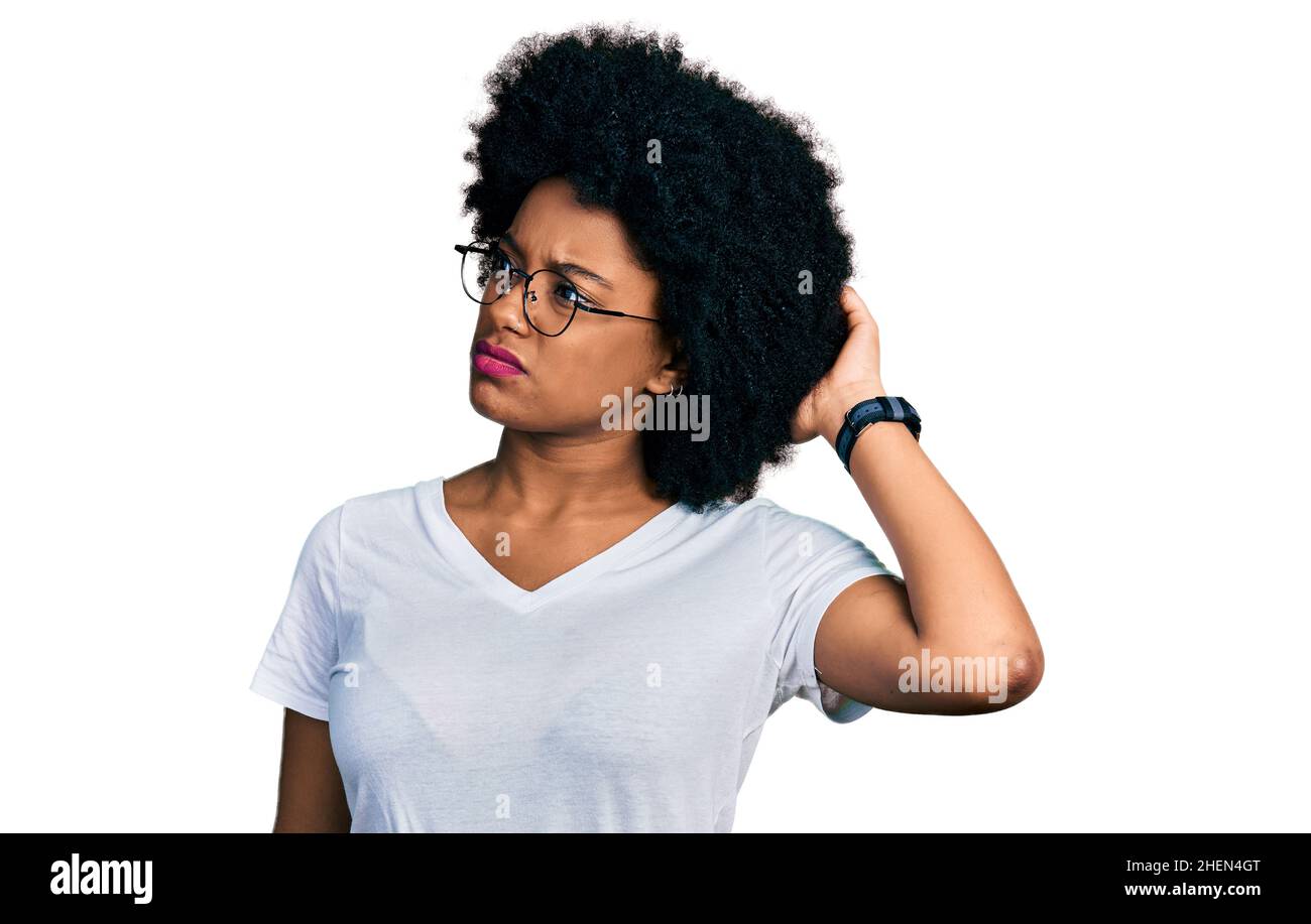 Giovane afroamericana che indossa una t shirt bianca casual confonde e si chiede di interrogarsi. Incerto con il dubbio, pensando con la mano sulla testa. Penne Foto Stock