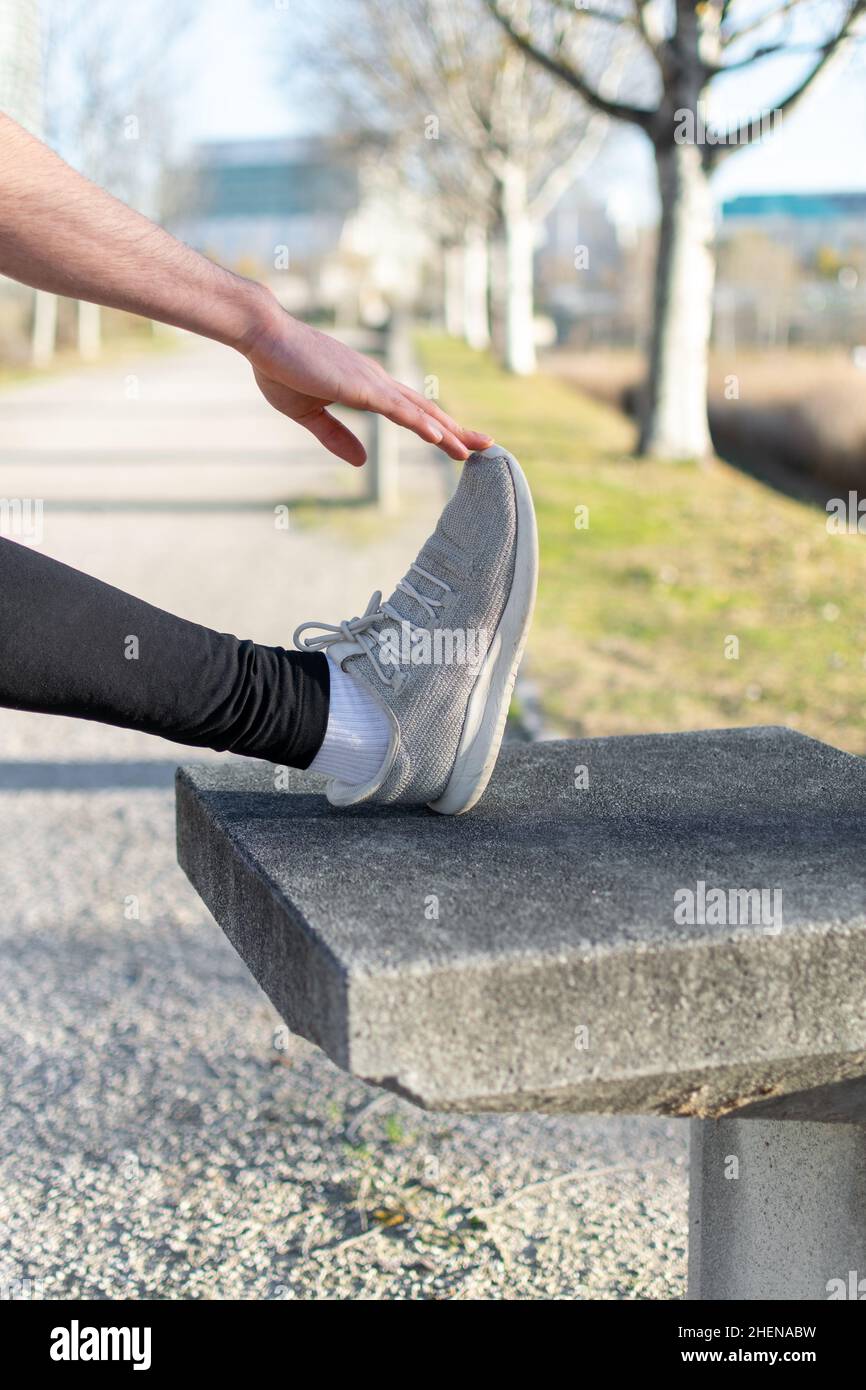 Un giovane runner irriconoscibile che allunga la gamba nel parco Foto Stock
