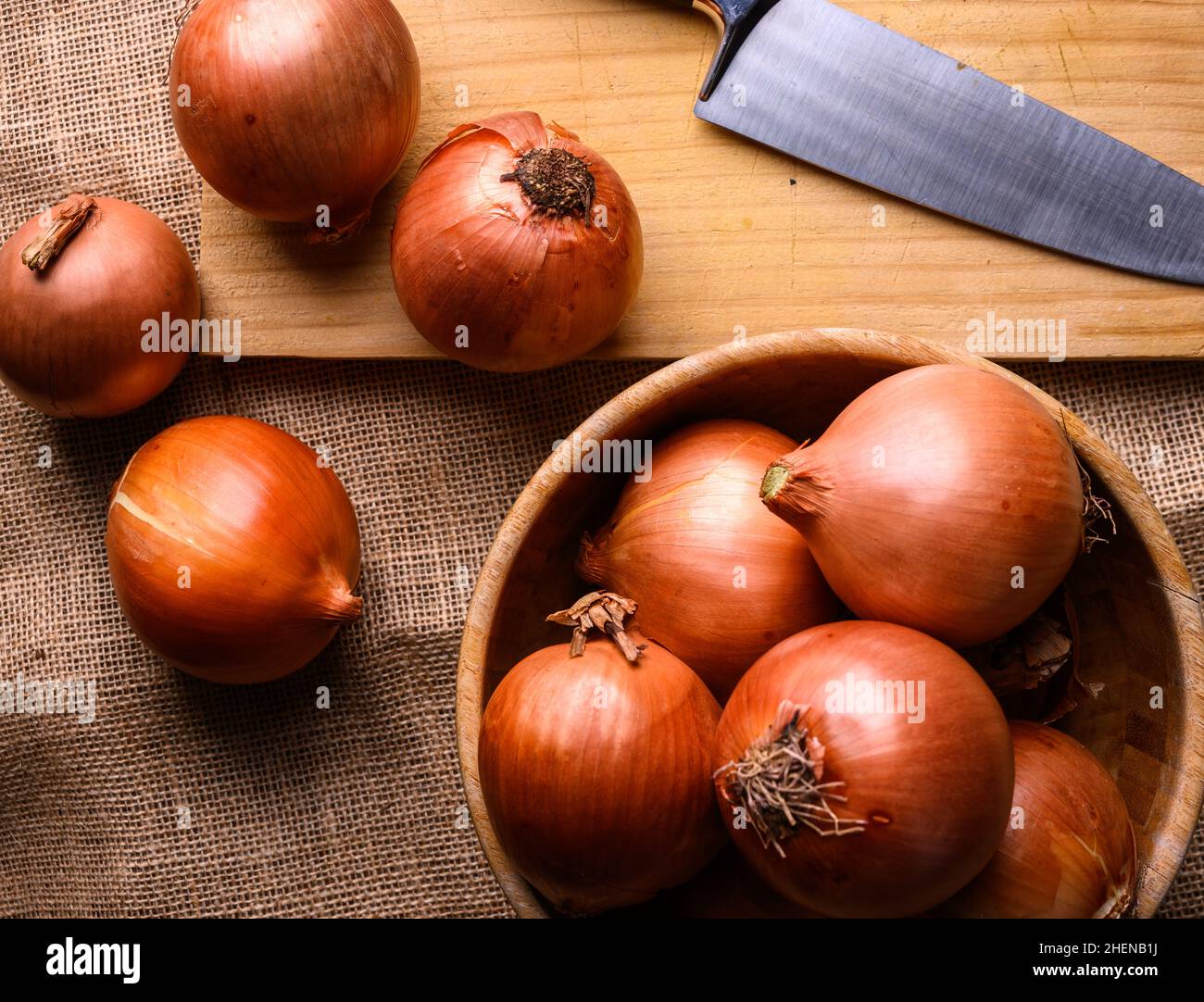 Cipolle rosse e bianche su un tagliere di legno e coltello su un rustico tavolo di legno in cucina, vista dall'alto. Foto di alta qualità Foto Stock