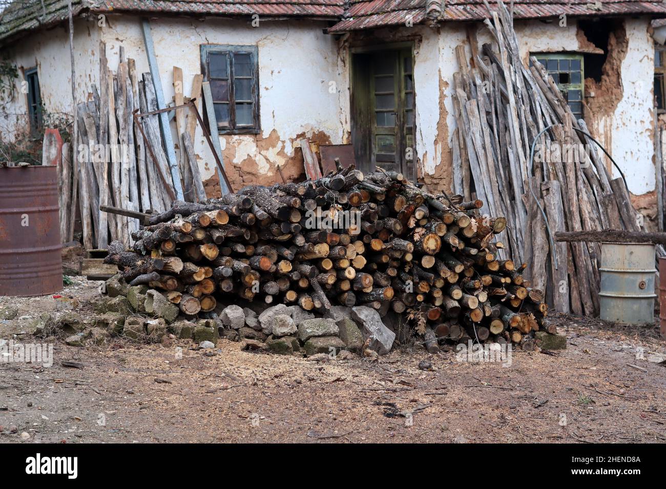 Un grande palo con alberi tagliati e parasoli allineati di fronte ad una vecchia casa nel villaggio Foto Stock