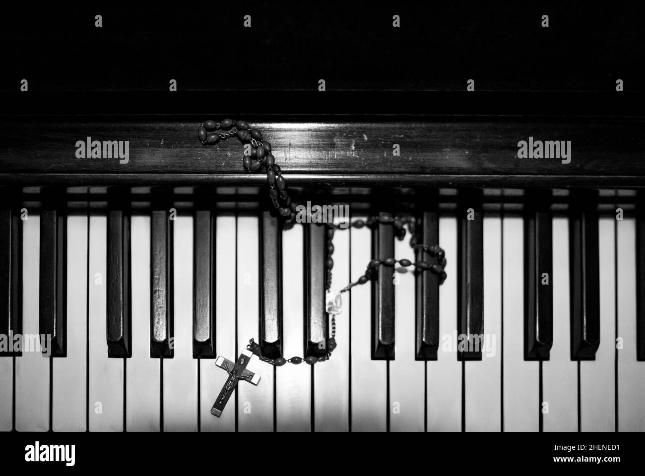 Un antico crocefisso e perle rosarie sulle chiavi di un antico pianoforte. Foto Stock