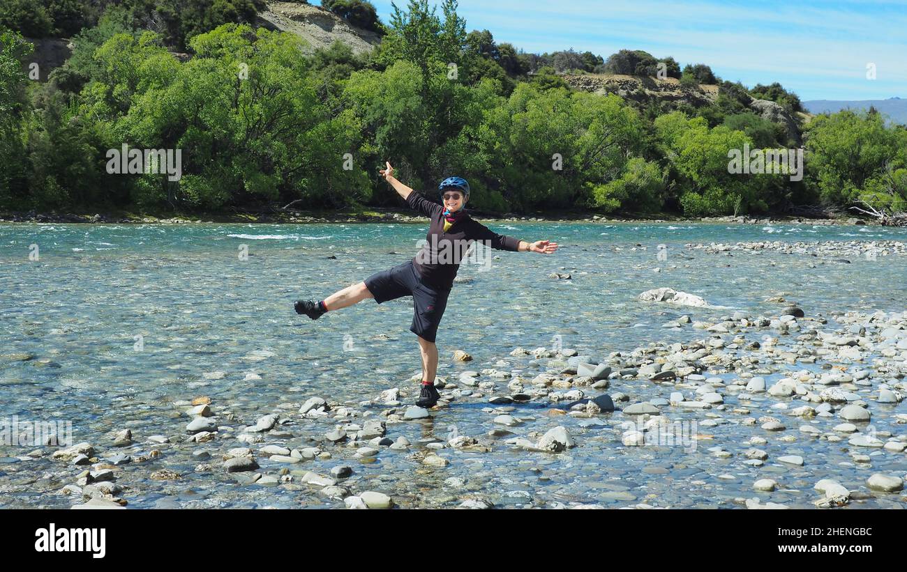 Una ciclista donna che volava intorno sul fiume Hawea, Nuova Zelanda Foto Stock